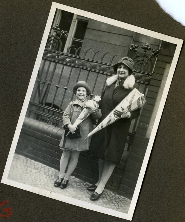 April 11, 1929, Eva stands with her mother on her first day of school holding a Schultute, or “school cone,” filled with candy and school supplies.